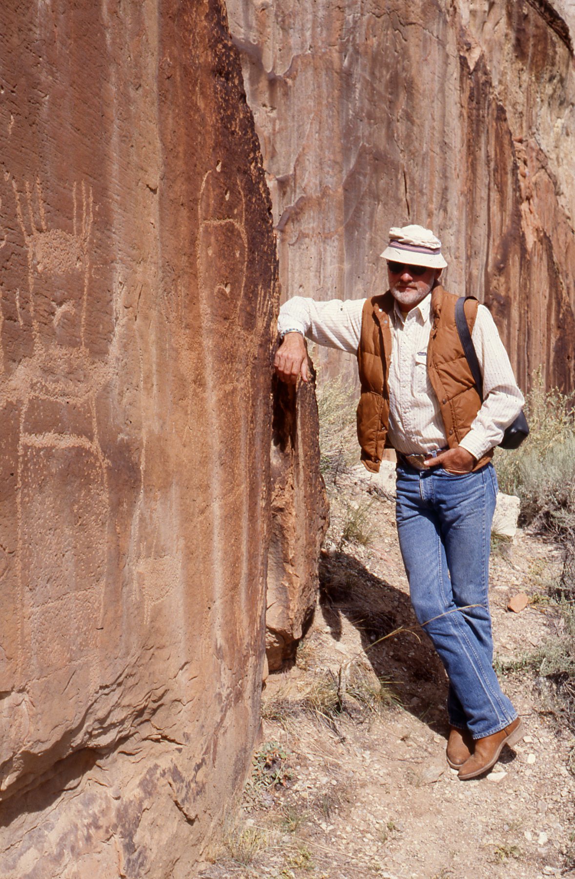 Dr. Charles Reher standing next to drawings on a rock face