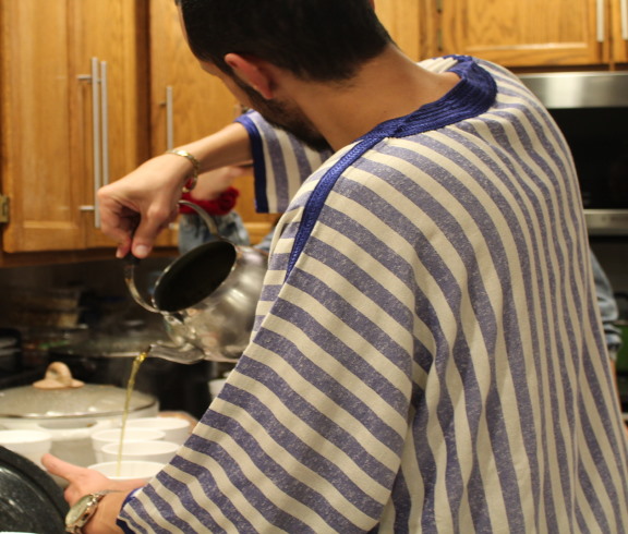 Fulbright student from morocco pouring tea at cultural event university of wyoming