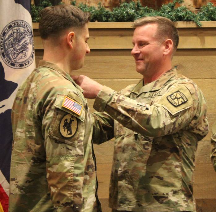 An officer pinning a badge on another.