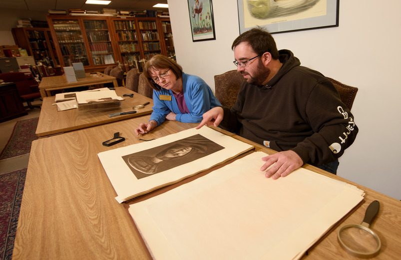 Two people examine an old photograph