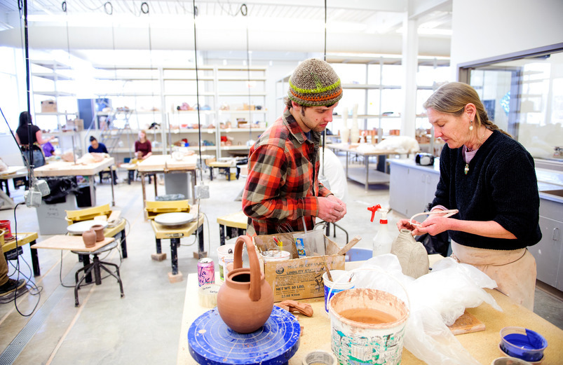 A professor checking out a student's pottery work in a studio