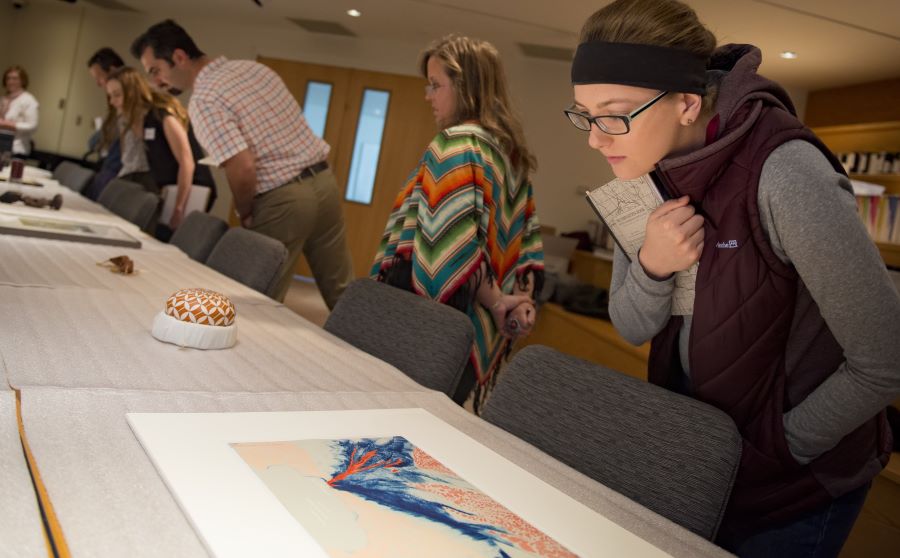 Student exmaining art on table