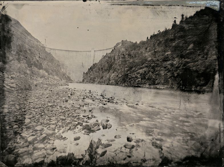 Black and White photograph of a canyon river with dam in the background