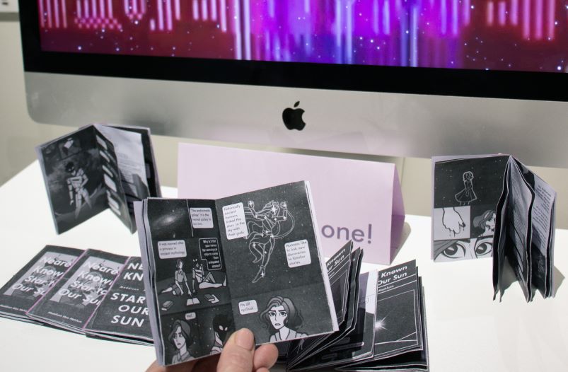 An art exhibition of digiallly deisgned zines with computer monitor in background.