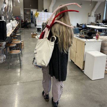 Art Student walking into the sculpture studio carrying project.