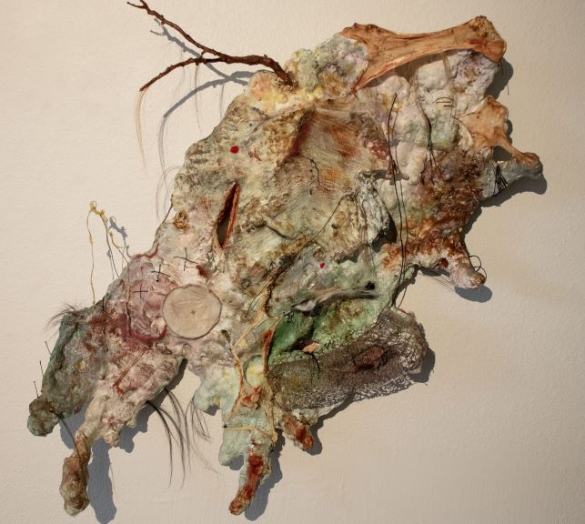3-D textured piece of art mounted on a white wall