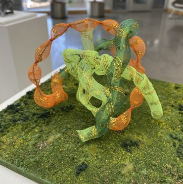 Green and Orange textured 3-D art mounted on a grassy appearing base