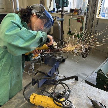 Student grinding metal in sculpture studio.