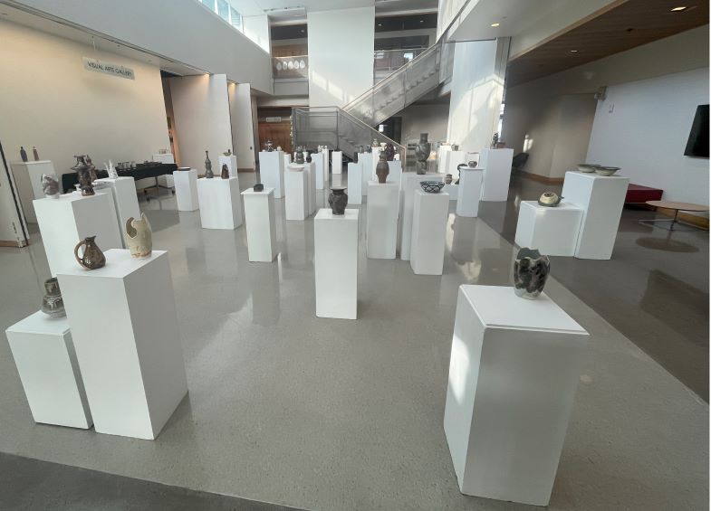 Several ceramic art pices displayed on pedestals in a building lobby 