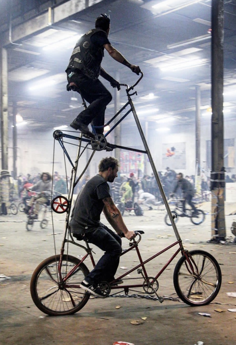 Two people riding a double decker bicycle.