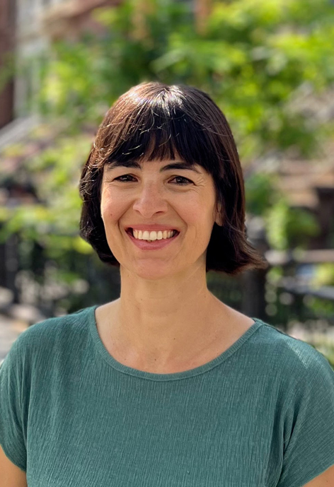 Headshot of person with green trees in background.
