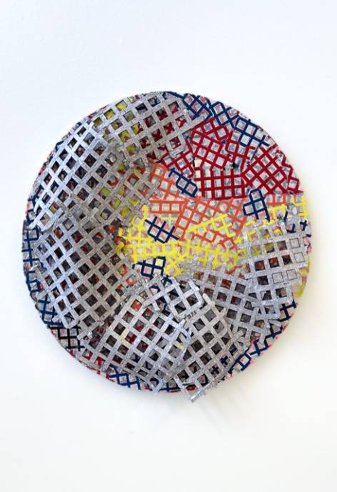 Circular ceramic sculpture of grey and multi-colored grates.