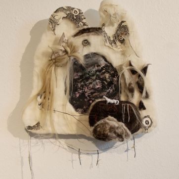 3-D textured piece of art mounted on a white wall