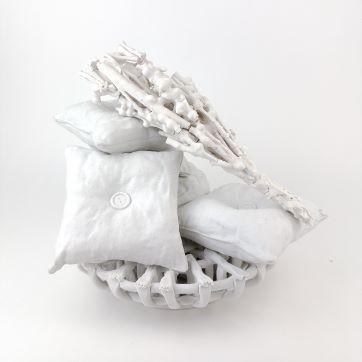 Cozy ceramic sculpture of pillows and a bouquet in a basket
