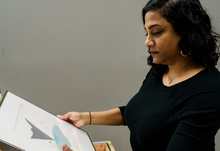 A curator at the University of Wyoming Art Museum examines a piece of art from the archives.