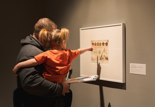 A parent holds a small child up to see a piece of art at the University of Wyoming Art Museum.