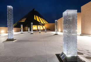 Outside the Centennial Center, a sculptural exhibit for the UW Art Museum is illuminated.