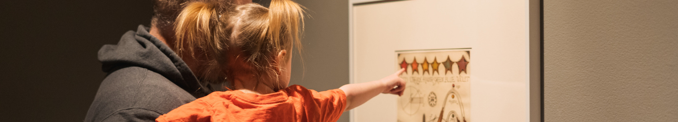 child pointing to a painring on exhibit.