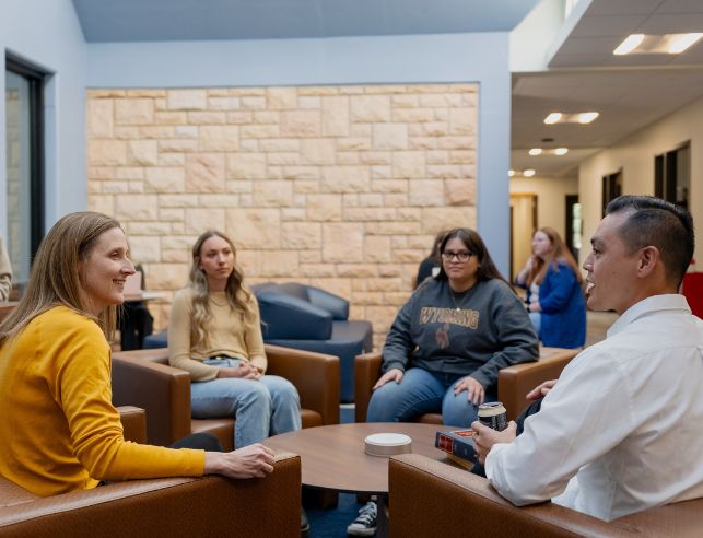 Students and faculty sit in the law building and chat.