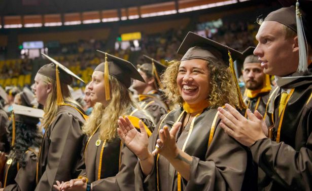 A&S graduates smile and clap at commencement