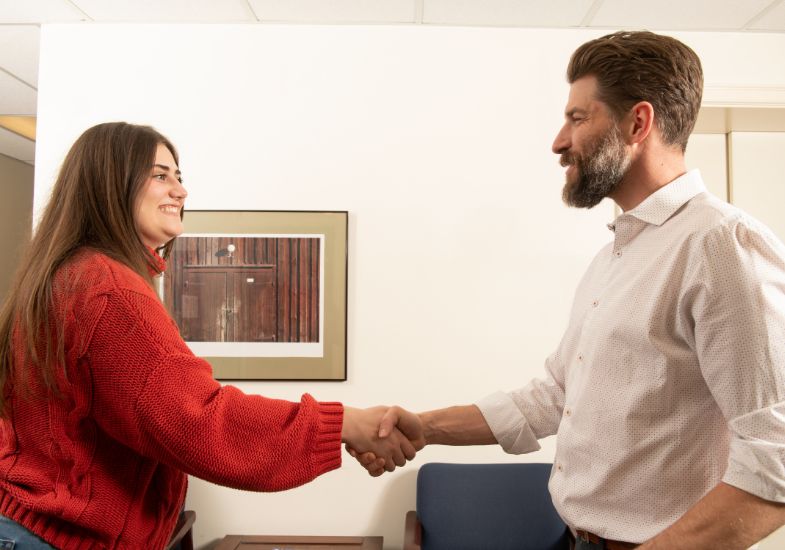 A student shakes hands with an advisor.
