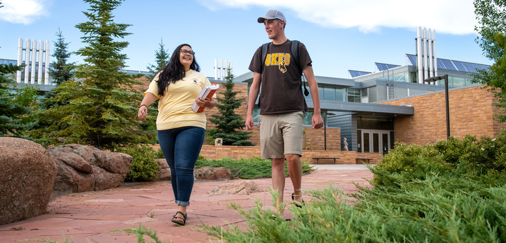 two students walking on campus together near visual arts building