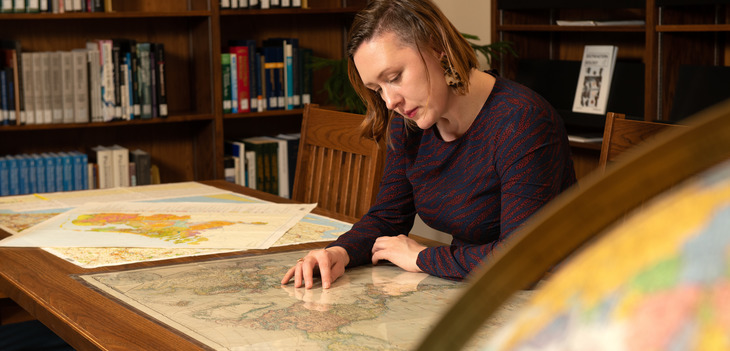 Student looking at maps in a library