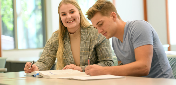 Two students study over a book together