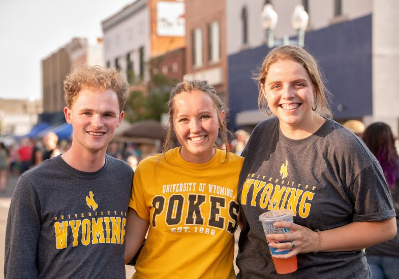 Three students smile and pose for a photo in downtown Laramie