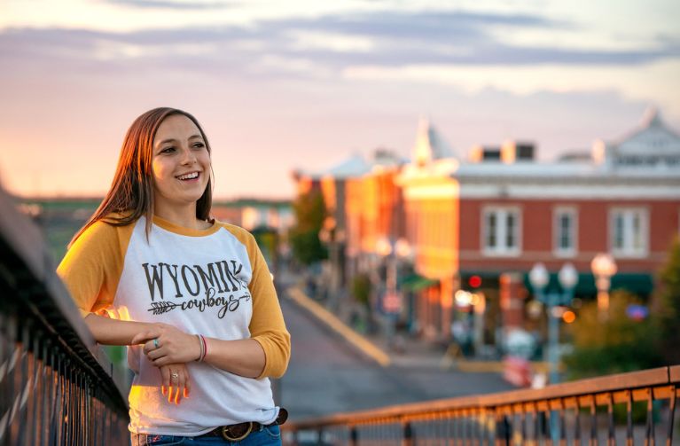 A women stands and smiles on the bridge in downtown Laramie.