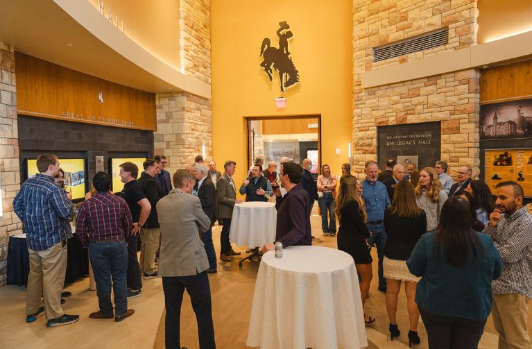 A large group of people stand and chat during an event at the Gateway Center.