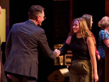 dean turpen shakes a student's hand who is crossing the stage