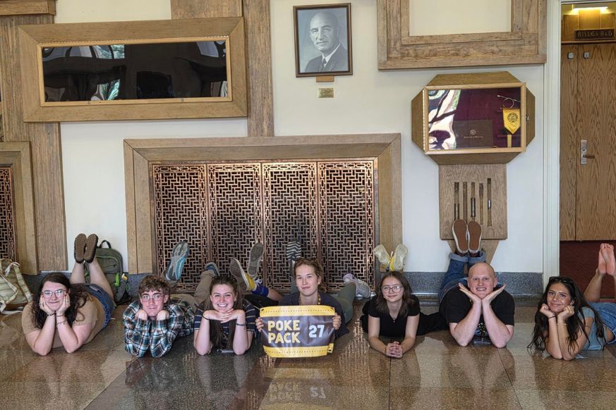 Saddle up students smile while laying on the floor in the A&S building