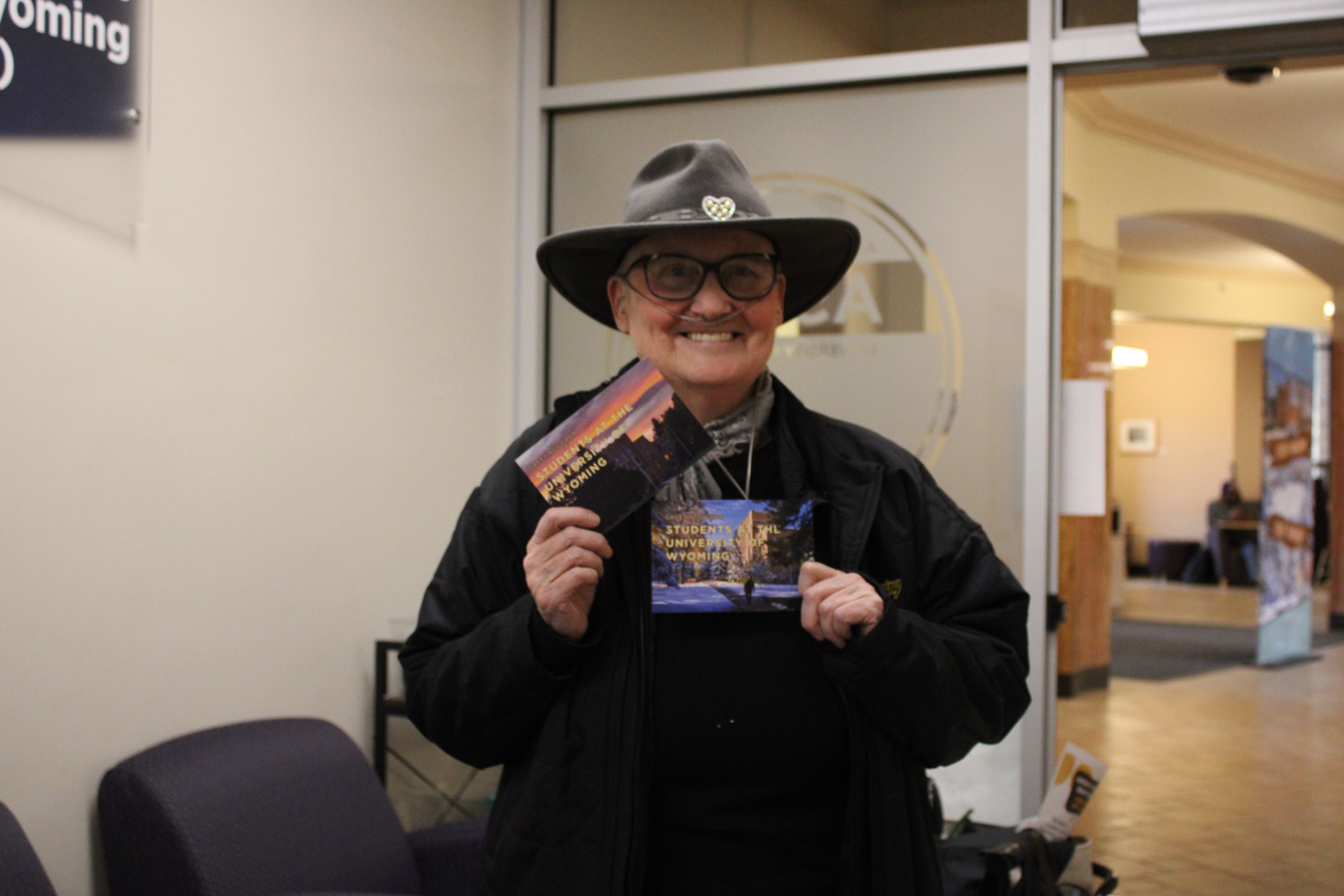 A woman holding up two ASUW Postcardse