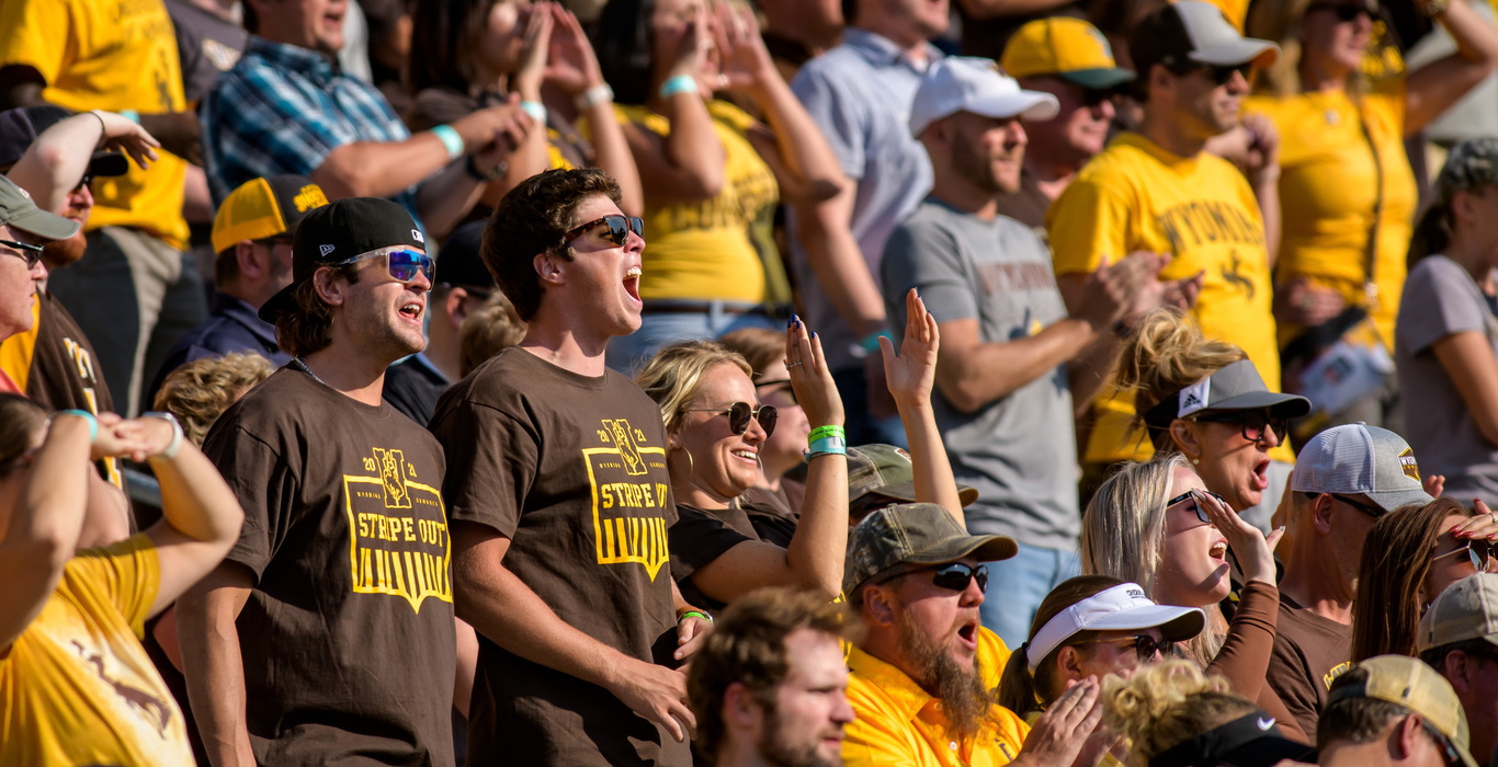 UW students and fans stand up and cheer during a football game at the University of Wyoming