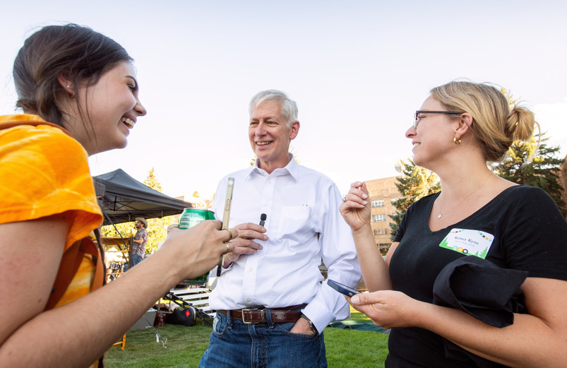A group of UW students and faculty chat and laugh at a UW event on the University of Wyoming campus