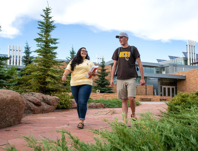 Two students walking with books, talking