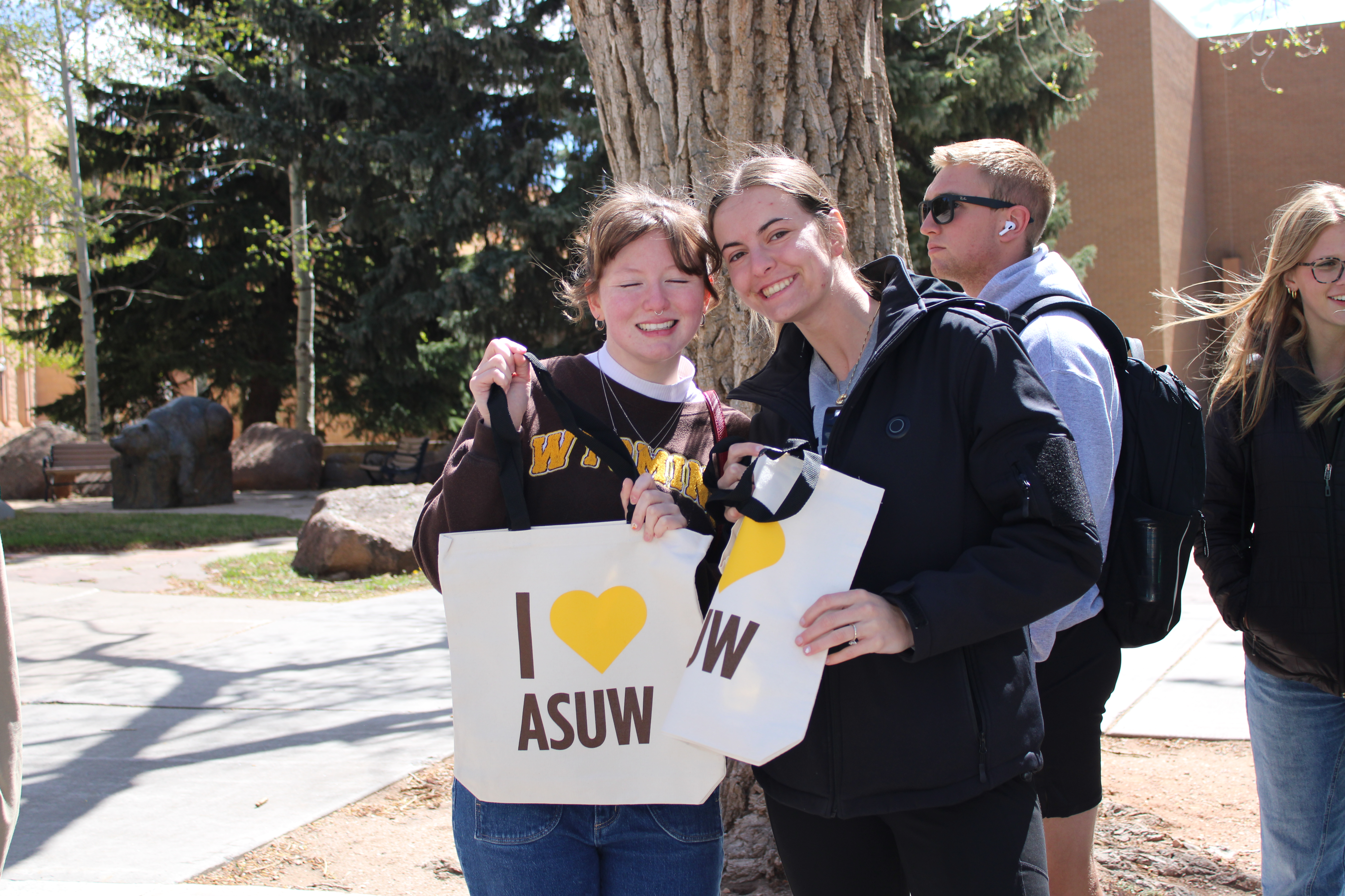 Students holding up tote bags that say "I love ASUW" 