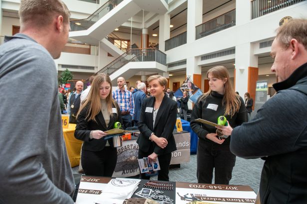 students gather at a booth at a career fair