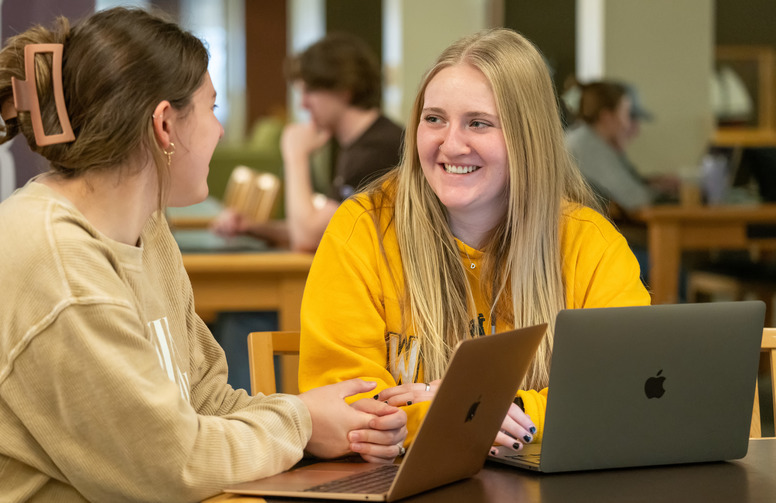 student smiling at each other while working together in the library