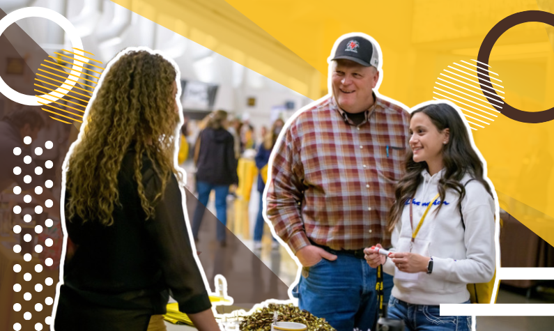 a new UW student and their parent chat with a staff member at a resource table.