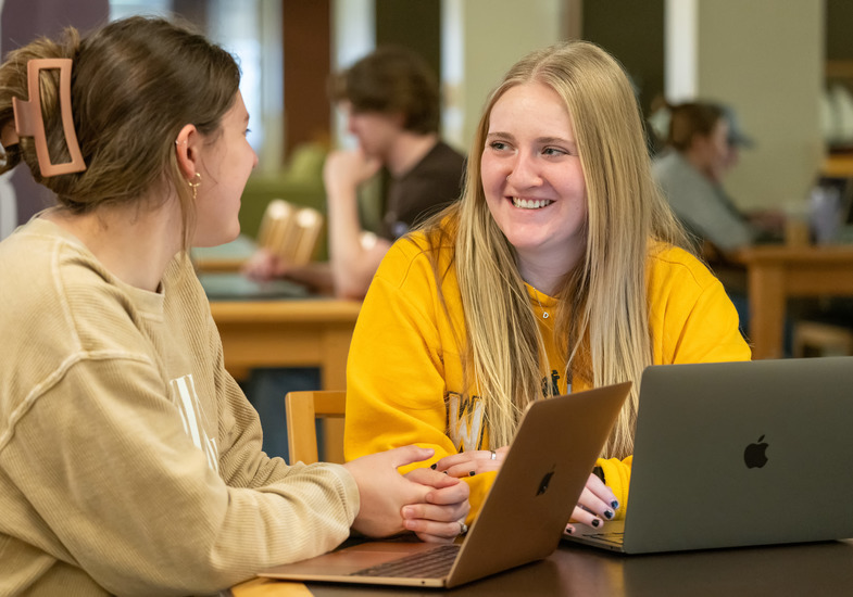 two student chat over a laptop