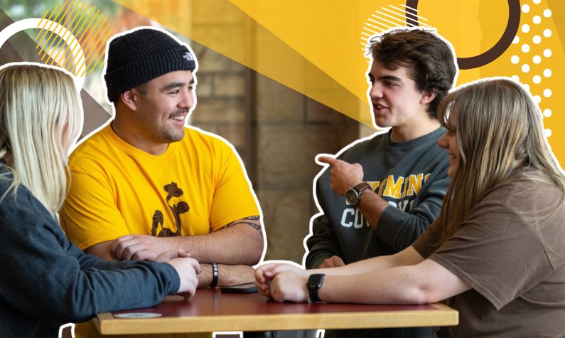 a group of four students at a table chatting 