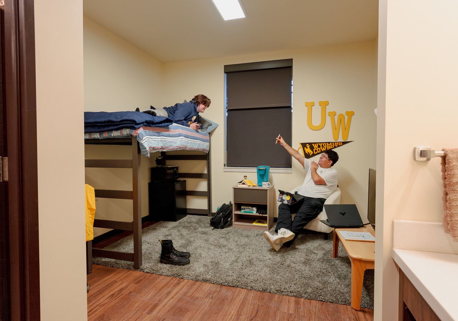 roommates hang out in thier dorm room showing each other memes