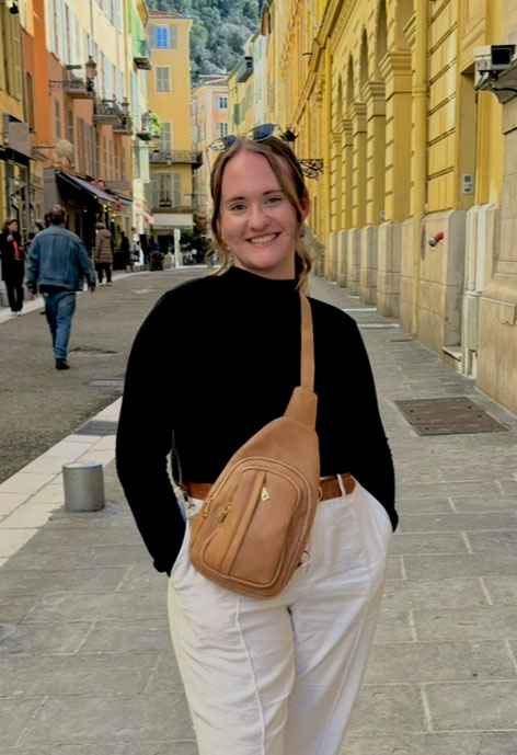 Picture of girl smiling in black shirt and white pants.