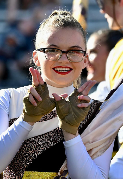 Woman smiling holding up finger guns in the shape of a "W" wearing Wester Thunder Marching Band Color Guarduniform.