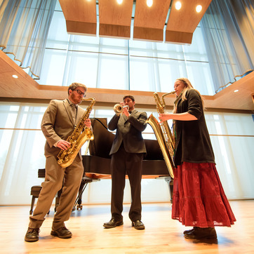 Group of three students performing on tenor saxophone, trumpet, and baritone saxophone in BCPA Recital Hall