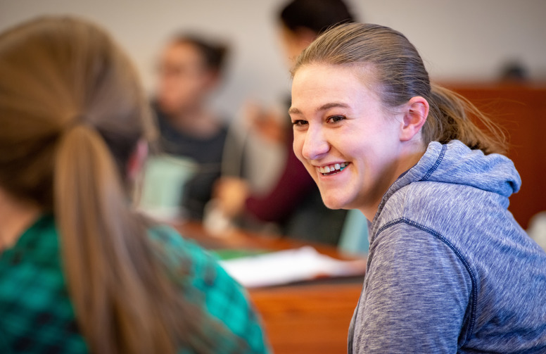 a student smiling at another in class 