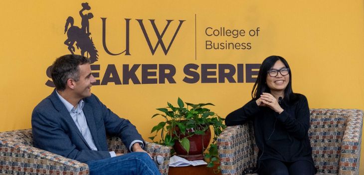 Dean of the College and guest speaker sit in front of a guest speaker backdrop addressing students