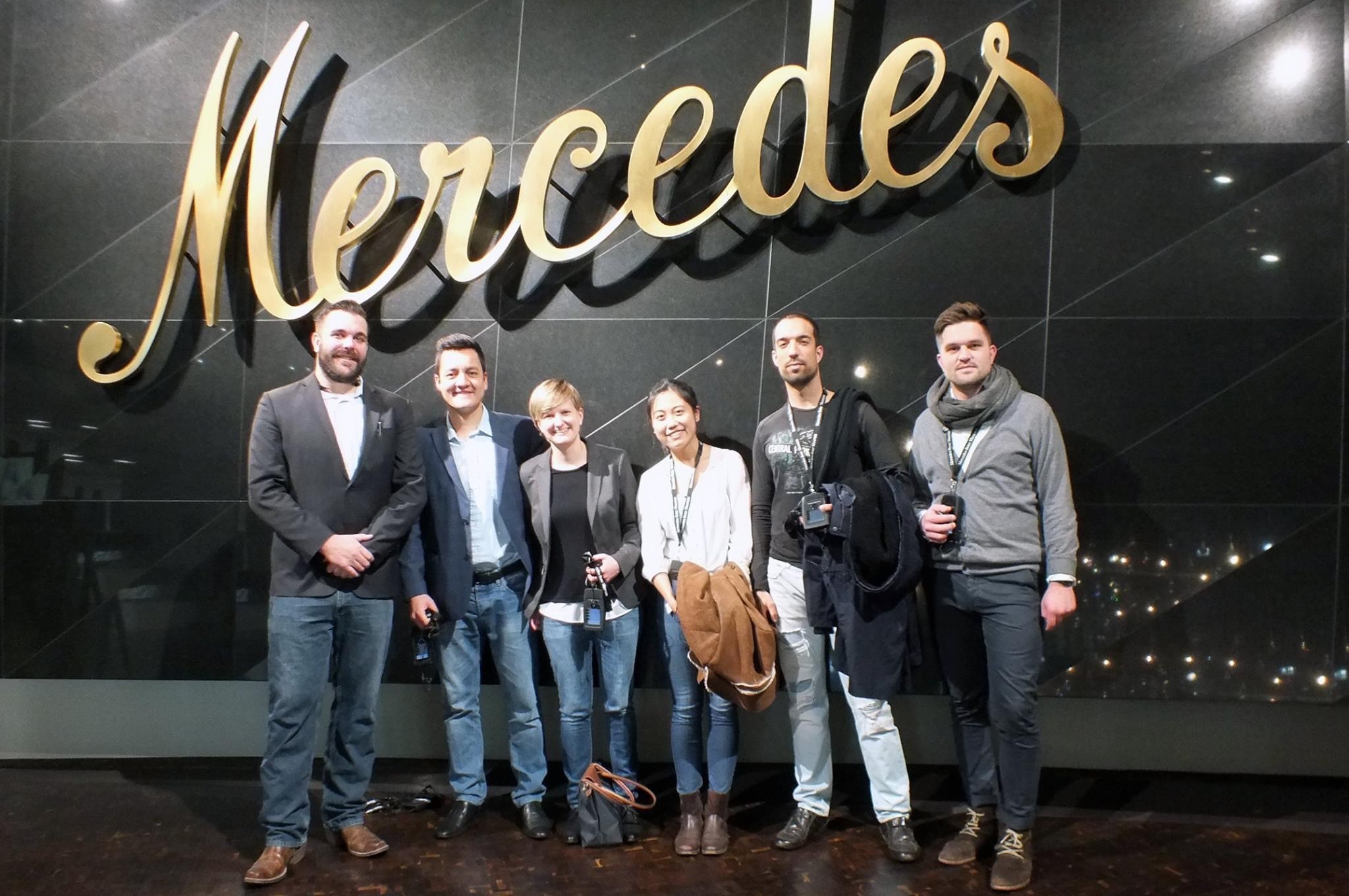 students in front of Mercedes sign